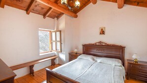 A bedroom with a wooden bed, a nightstand, a bench, a window, and a small wall decoration. - 2 bedroom nice home in Sovramonte (Sovramonte)