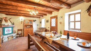 A rustic dining area with a wooden bench, a table set for two, and a fireplace with a coat of arms. - 2 bedroom nice home in Sovramonte (Sovramonte)