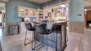 Una cucina moderna con isola centrale, sgabelli da bar e frigorifero in acciaio inossidabile.