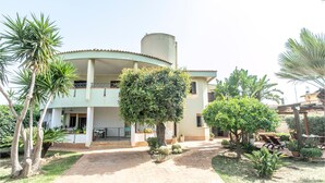 A two-story building with a curved roof, a central courtyard, and various potted plants. - 1 bedroom lovely home in Siracusa (Siracusa)