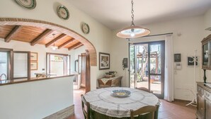 A dining area with a round table, chairs, and a ceiling fan. There is a kitchen area with a counter and cabinets, and a door leading outside. - 1 bedroom lovely home in Siracusa (Siracusa)