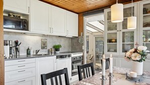 Une cuisine moderne avec des armoires blanches, un four encastré et un coin repas agrémenté d’une nappe à motifs floraux.