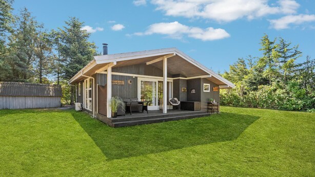 Une cabane en bois dotée d’un porche abrité, d’un coin repas et d’un petit espace salon.