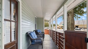 A covered porch with wicker chairs, a wooden gate, and a view of the street. - 🌟Downtown Pensacola Getaway!🌟 Fenced in yard for fur babies! (Pensacola)