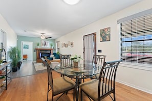 A dining area with a glass table and chairs, a fireplace, and a view of the outdoors through large windows.