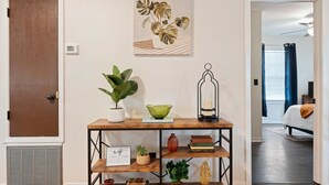 A room with a wooden console table, a potted plant, a green bowl, a lantern, and a framed picture. - 🌟Downtown Pensacola Getaway!🌟 Fenced in yard for fur babies! (Pensacola)
