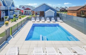 Une piscine dotée de plusieurs chaises longues et d’un espace salon abrité.