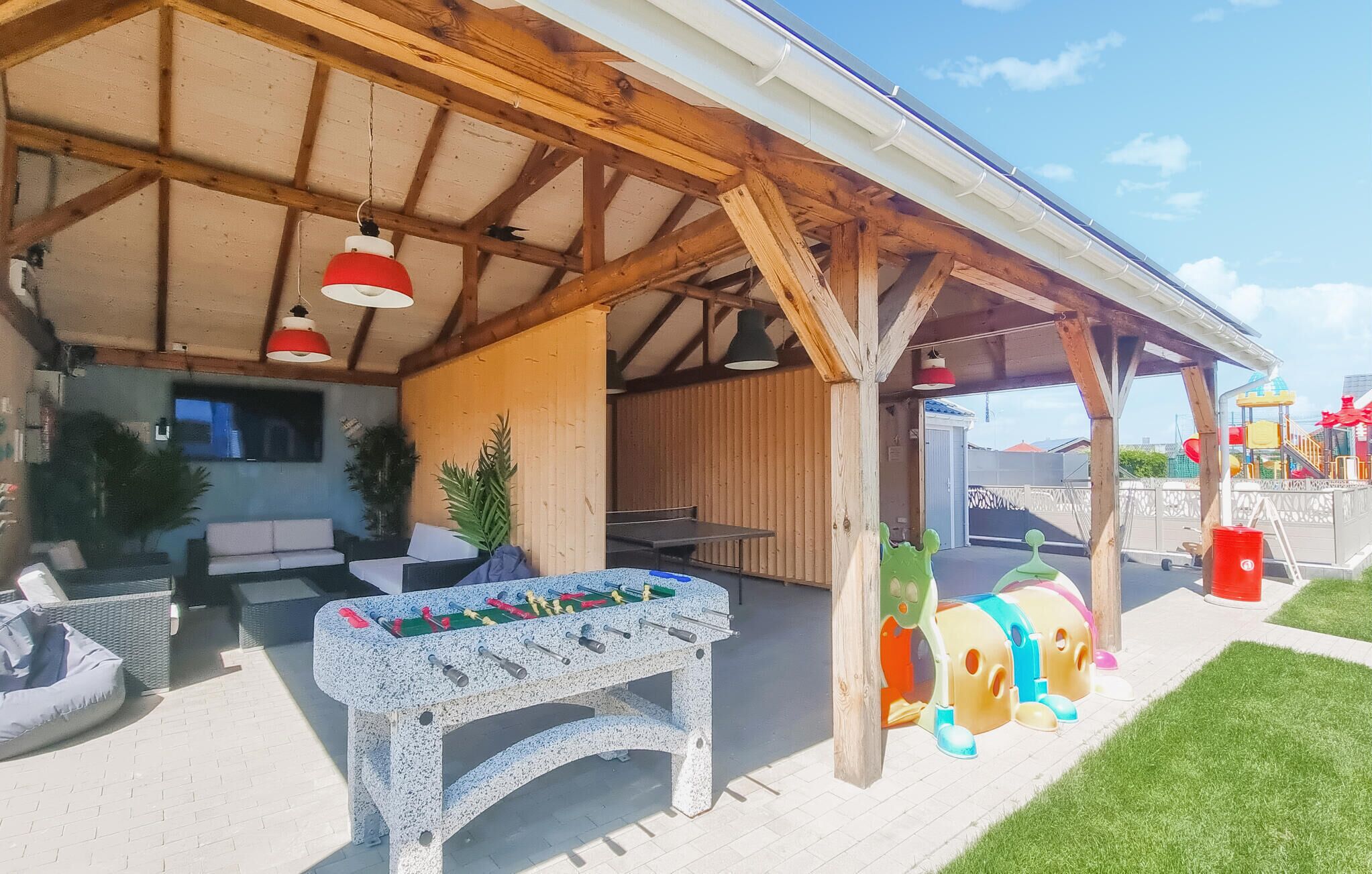 Un patio al aire libre con mesa de piedra, asientos y juegos infantiles.
