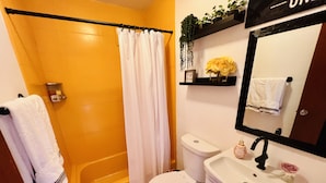 A bathroom with a bathtub, toilet, sink, and a mirror.
