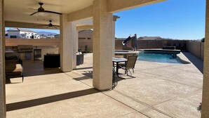 A covered outdoor patio with a pool, barbecue area, and seating. - Colorado River Getaway, Resort Pool, Waterslide & Mountain Views (Fort Mohave)