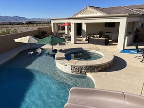 A swimming pool with a hot tub, outdoor furniture, and a covered patio area. - Colorado River Getaway, Resort Pool, Waterslide & Mountain Views (Fort Mohave)