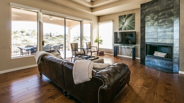 Un salón amplio con un sofá de cuero, una chimenea y ventanas grandes que ofrecen vistas al exterior.