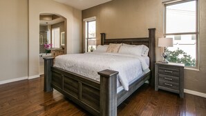Un dormitorio con cama de madera, una mesita de noche, una lámpara y ventana con vistas.