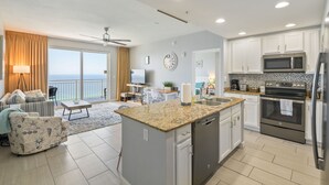 A modern kitchen with white cabinets, a granite countertop, stainless steel appliances, and a view to the outside.