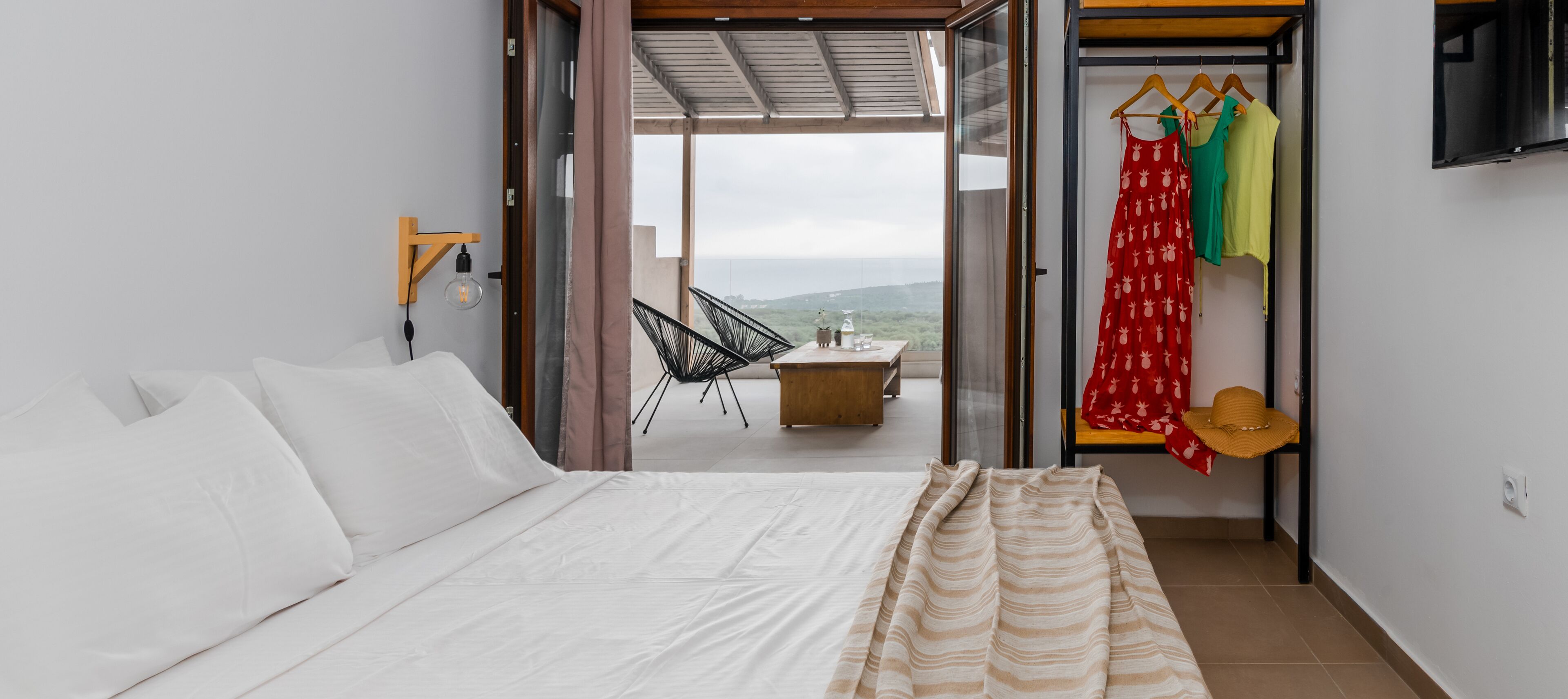Ein Schlafzimmer mit einem Bett, einem Hängestuhl und Blick ins Freie.