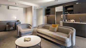 Una sala de estar moderna con un sofá, dos sillones, una mesa de centro y estanterías empotradas con objetos decorativos.