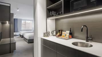 Habitació d'hotel moderna amb petita cuina, un llit i vistes a l'exterior.