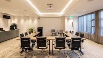 Una sala conferenze con un lungo tavolo, sedie nere e un moderno design del soffitto.