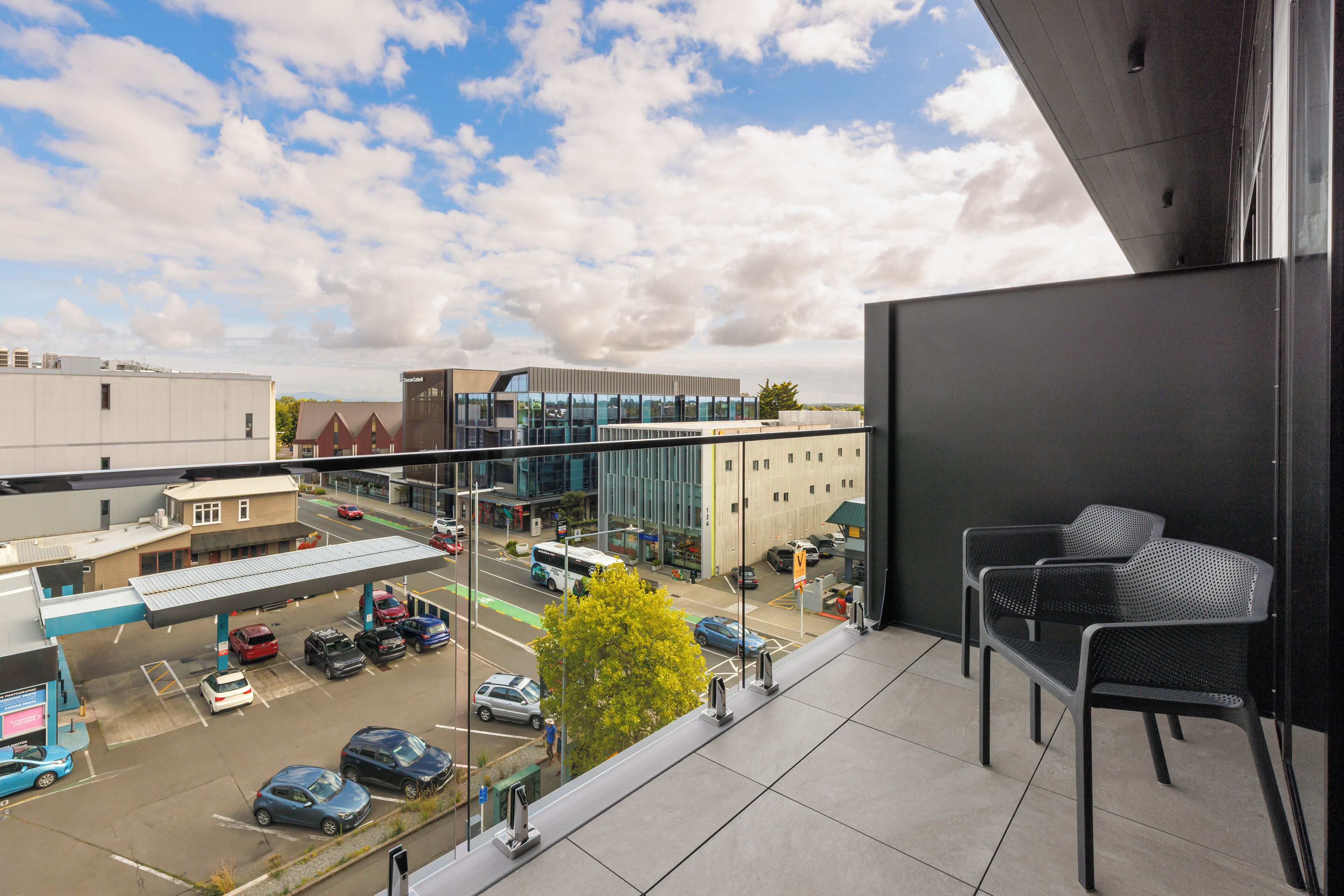 A balcony with a view of a parking lot and buildings, including a modern glass structure.