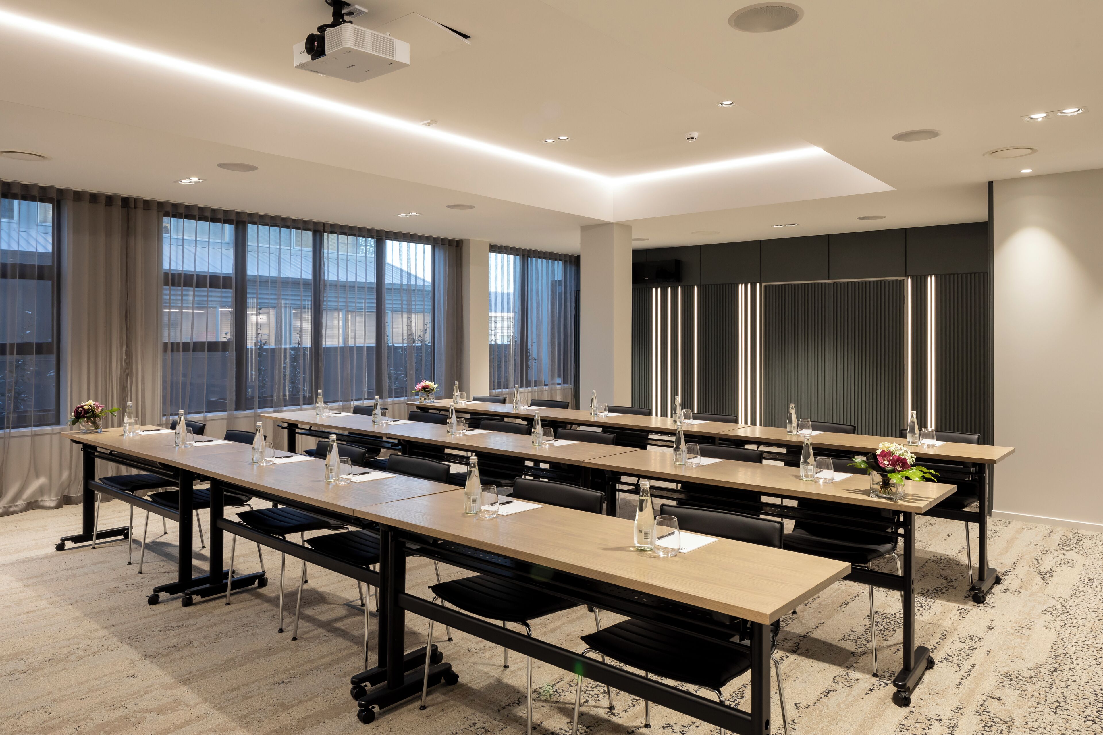 A conference room with long tables, chairs, and a projector.