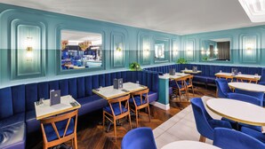 A restaurant with blue booths, wooden tables, and chairs. - The Mayfair (Christchurch)