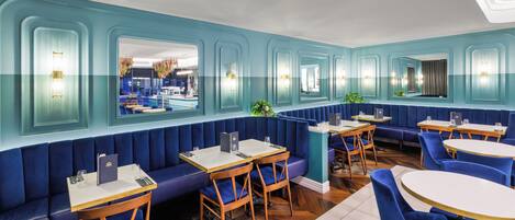 Un restaurante con asientos azules, mesas y sillas de madera.
