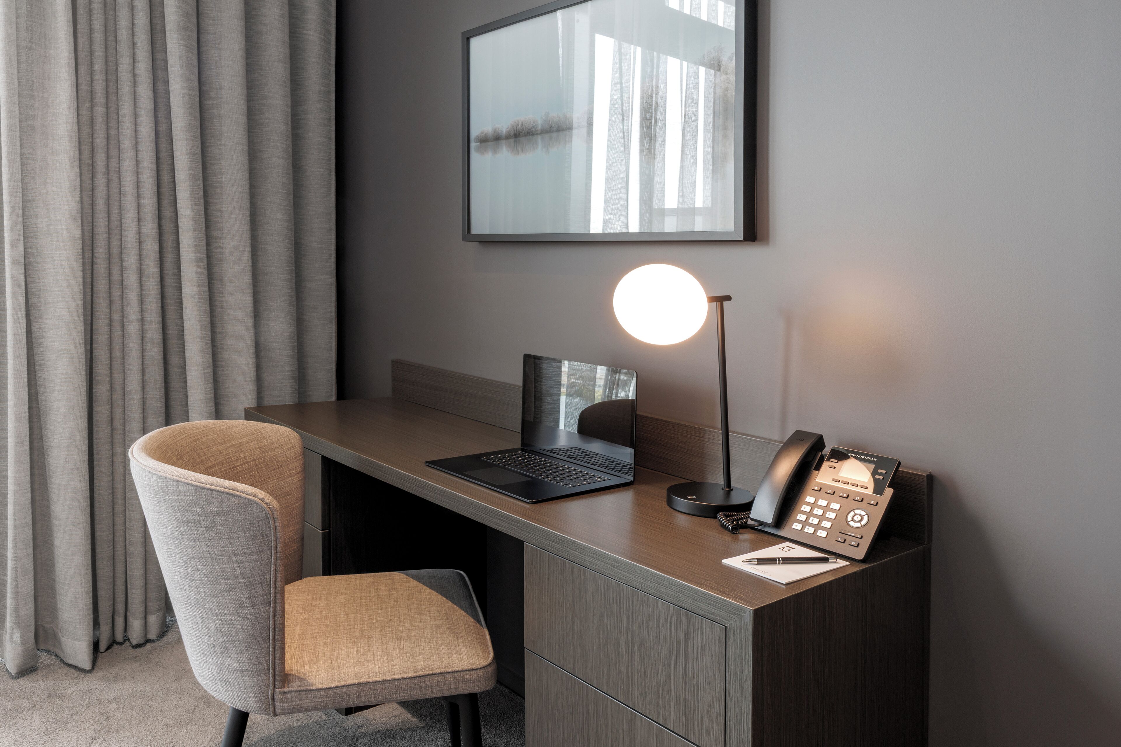 A modern office desk with a laptop, a desk lamp, and a telephone.