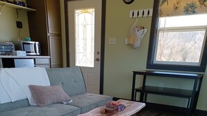 Un salon avec un canapé gris, une table basse en bois et un tapis à motifs.
