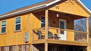 Une maison en bois à deux étages, dotée d’un porche, d’une porte bien visible et d’une fenêtre.