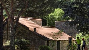 Un edificio de piedra con techo de tejas, rodeado de árboles y follaje.