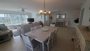 A spacious living room with a dining area, a TV, and a ceiling fan.