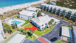 Luftaufnahme eines Küstenresorts mit Schwimmbad, mehreren Gebäuden und Strand.