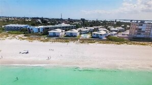 Ein Strandgrundstück mit mehreren weißen Gebäuden, einem Sandstrand und freiem Blick auf den Ozean.