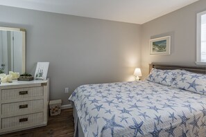 A bedroom with a bed, dresser, and a painting on the wall. - Ocean block condo in the heart of Beach Haven. (Beach Haven)