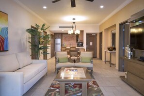 A spacious living room with a sofa, two armchairs, a coffee table, and a dining area with chairs and a chandelier.