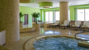 Un espace spa comprenant un jacuzzi, des chaises longues et de grandes fenêtres.