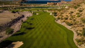 Un parcours de golf offrant une vue sur la mer et les montagnes en arrière-plan.