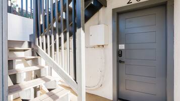 A staircase leading to a door marked with the number 201, a white wall, and a small air conditioning unit.