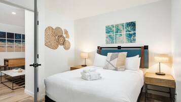 A modern hotel room with a large bed, two bedside tables, a desk, and a chair.