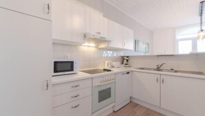 Une cuisine moderne avec des meubles blancs, un four à micro-ondes, une cuisinière et un évier.