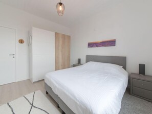 Un dormitorio con cama, mesitas de noche, armario y un cuadro en la pared.