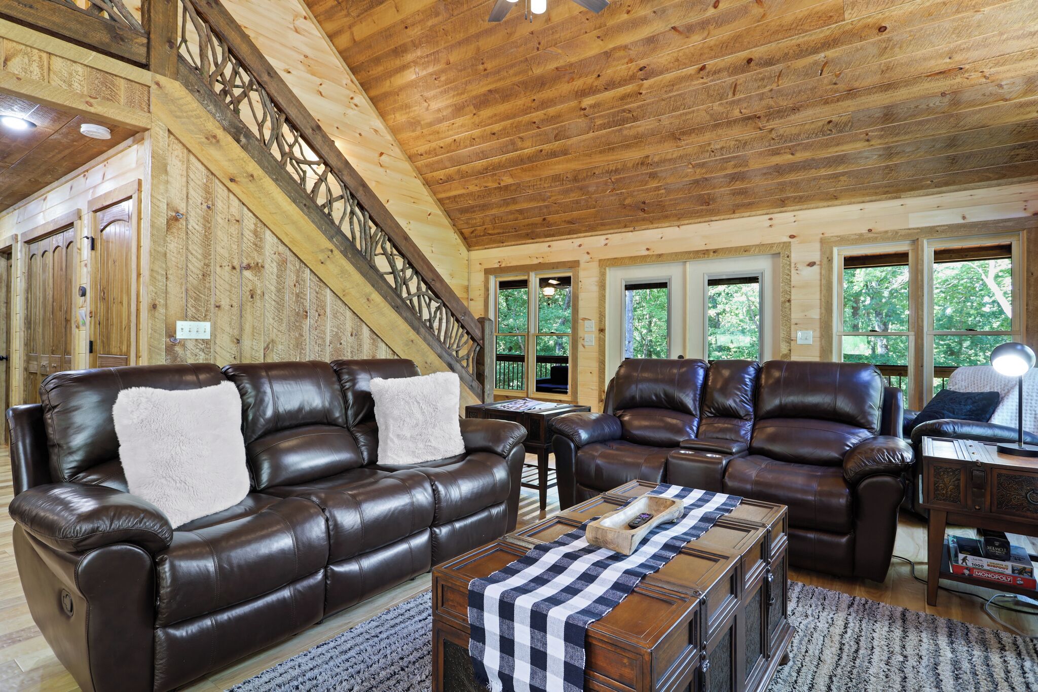 A spacious living room with leather sofas, a coffee table, and a staircase with wooden railings.