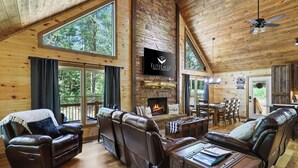 A spacious living area with leather sofas, a fireplace, and a large TV screen displaying 'Elite Eagle Realty Services'.