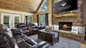 A cozy living room with a leather sofa, a fireplace, and a mounted television displaying 'ELITE EAGLE REALTY SERVICES'.