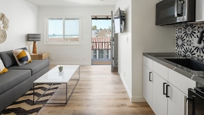 A modern kitchen with white cabinets, a black countertop, and a built-in microwave.