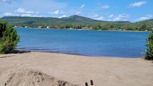 A yellow beach toy on a sandy beach with a lake and mountains in the background. - Beautiful Lake House for Rent (Neebing)