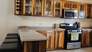 A kitchen with wooden cabinets, a microwave, an oven, and a bar area with stools. - Spacious Property with awesome scenic views-10 minutes from Ocho (Tower Isle)