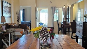 A wooden dining table with a vase of pinecones and yellow flowers, a red placemat, and a hanging light fixture. - Spacious Property with awesome scenic views-10 minutes from Ocho (Tower Isle)
