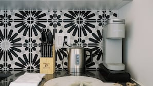Una cocina con cafetera, hervidor y bloque de cuchillos.