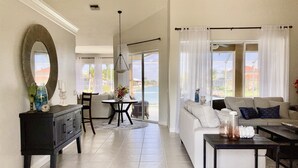 A spacious living area with a large sofa, a dining table, and a kitchen area. - 8 Minute Walk to Beach Luxury 4 Bdrm Waterfront home -salt water heated Pool (Marco Island)